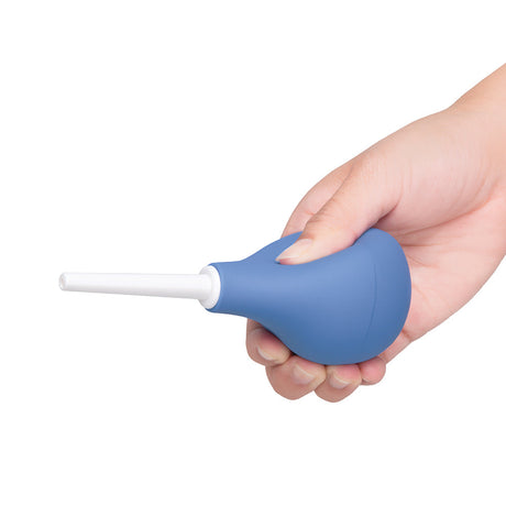 b-Vibe Compact Enema Douche Blue held in a hand, showcasing its ergonomic design and travel-friendly features.
