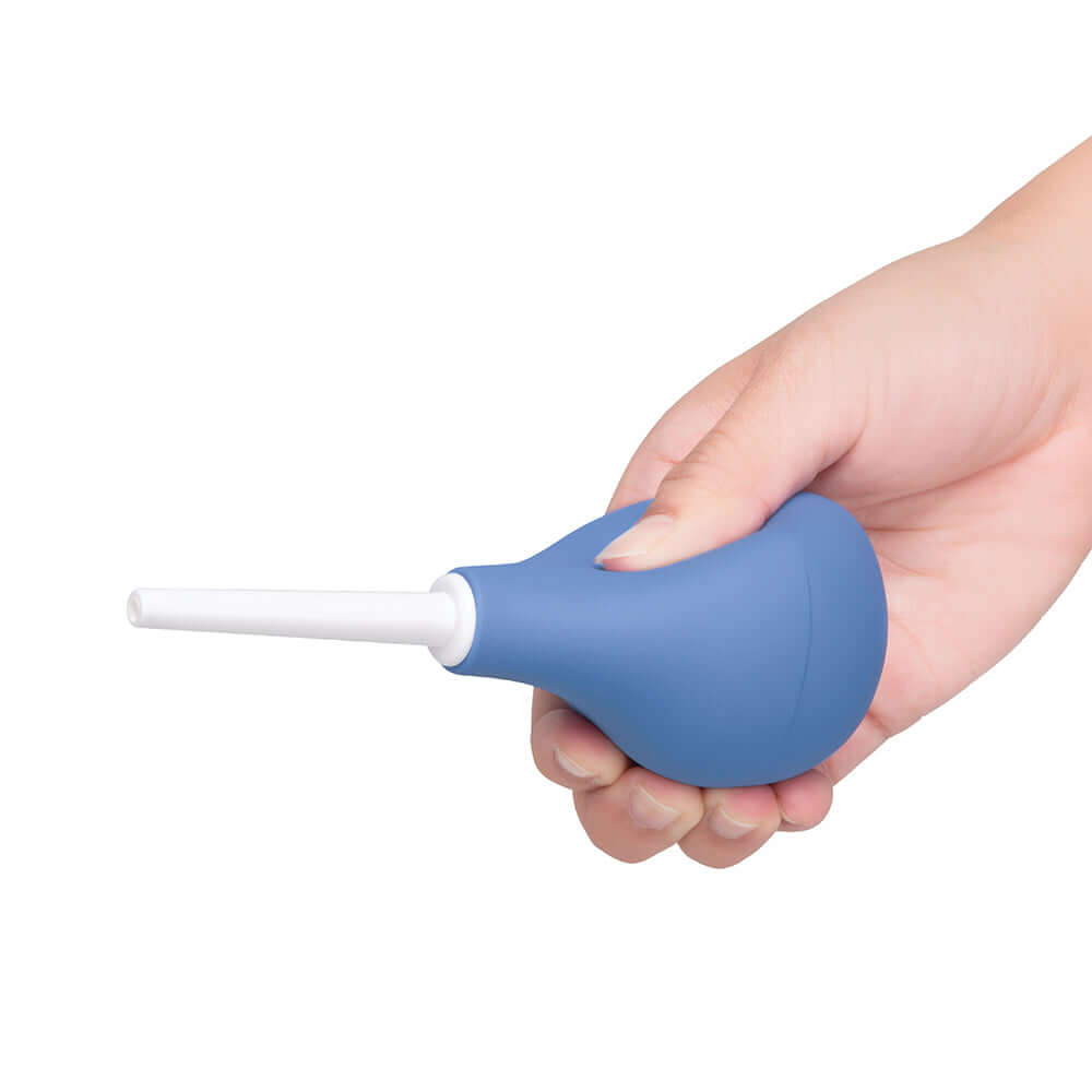 b-Vibe Compact Enema Douche Blue held in a hand, showcasing its ergonomic design and travel-friendly features.