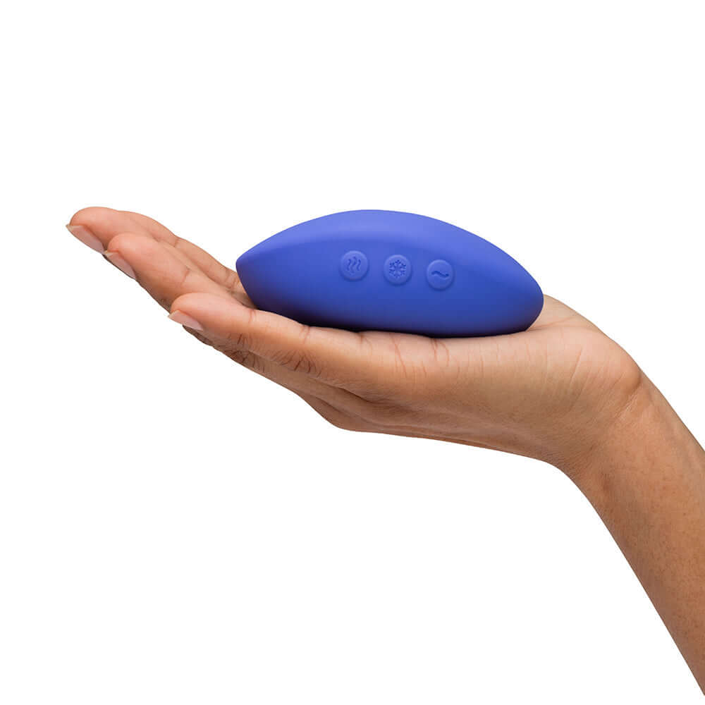 We-Vibe Temp Clitoral Massager Lavender Blue held in a hand, showcasing its ergonomic design and controls.