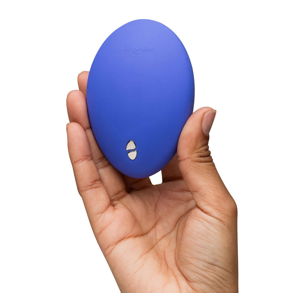 We-Vibe Temp Clitoral Massager Lavender Blue held in a person's hand, showcasing its sleek design and color.