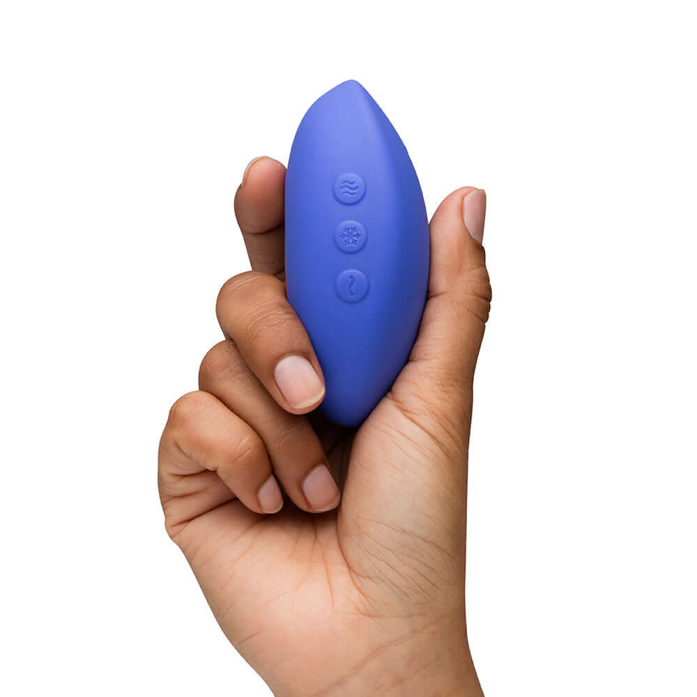 We-Vibe Temp Clitoral Massager Lavender Blue held in hand, showcasing its ergonomic design and control buttons.