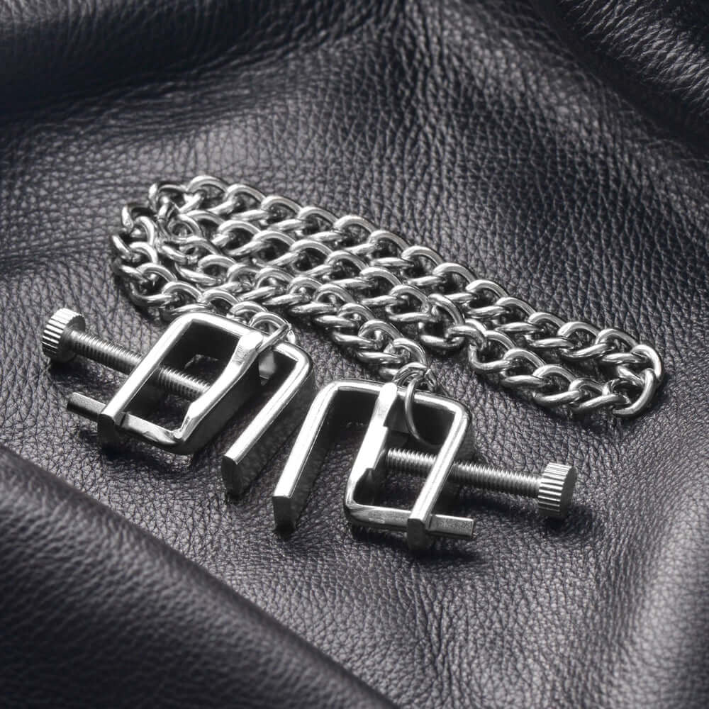 Master Series Pressure Vice Metal Nipple Clamps on a black leather background with a chain.