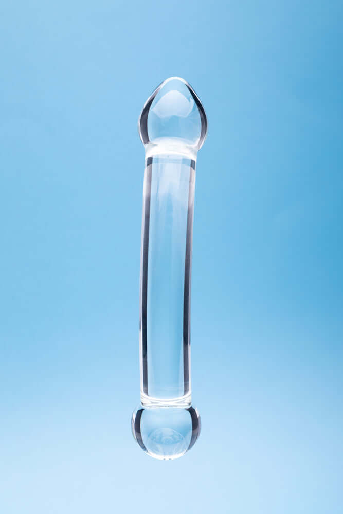 Clarity Celestial Purity Glass Dildo against a blue background, showcasing its elegant design and craftsmanship.