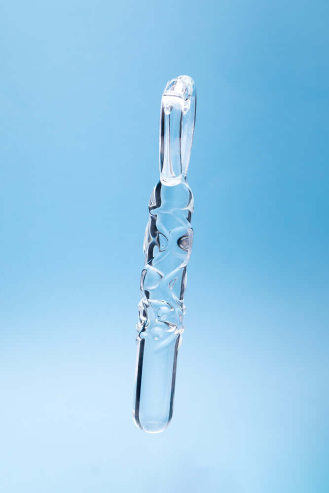 Clarity Heras Caress Glass Dildo hanging against a blue background, showcasing its elegant design and craftsmanship.