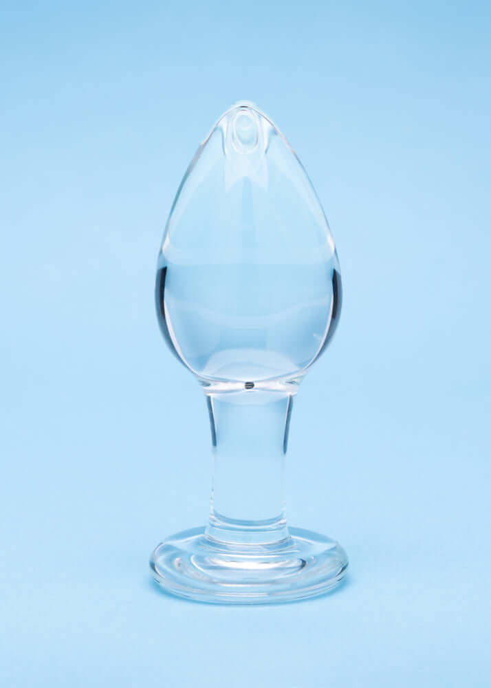 Clarity Utopian Trinity Glass Plug Set displayed against a blue background, showcasing the elegant design of a glass butt plug.