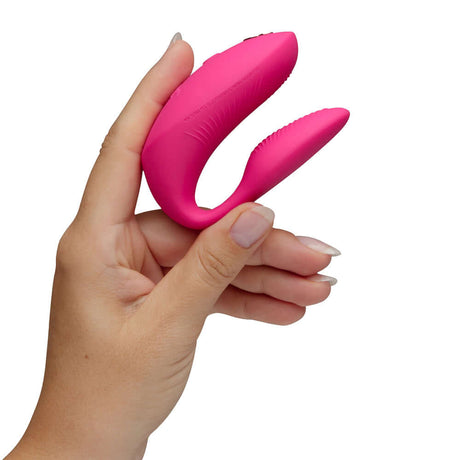 We-Vibe Chorus Pro Couples Massager Electric Pink held in hand, showcasing its ergonomic design and vibrant color.