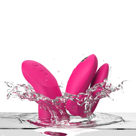 We-Vibe Chorus Pro Couples Massager Electric Pink splashing in water, showcasing vibrant color and design.