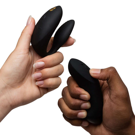 We-Vibe Chorus Couples Vibrator with Remote Control Black held by two hands, showcasing its user-friendly design.