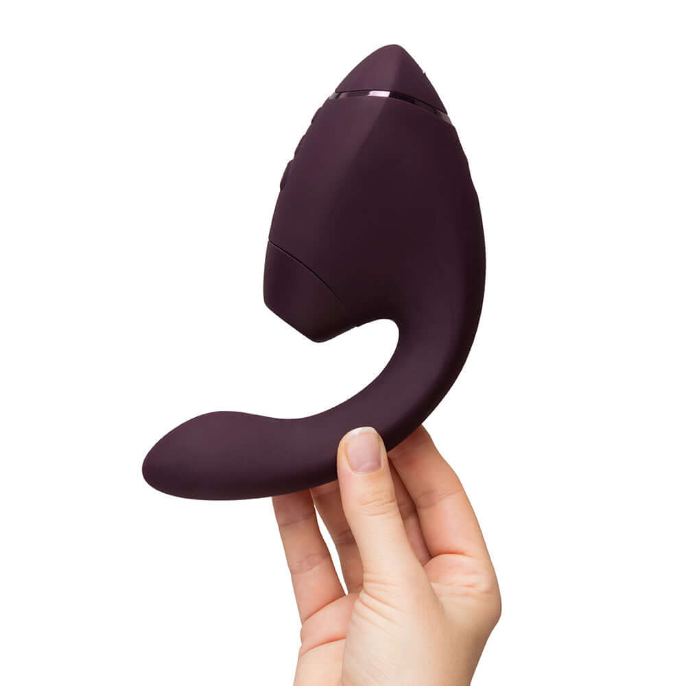Womanizer Next Duo Massager Dark Purple held in hand, showcasing its unique design and luxurious features.