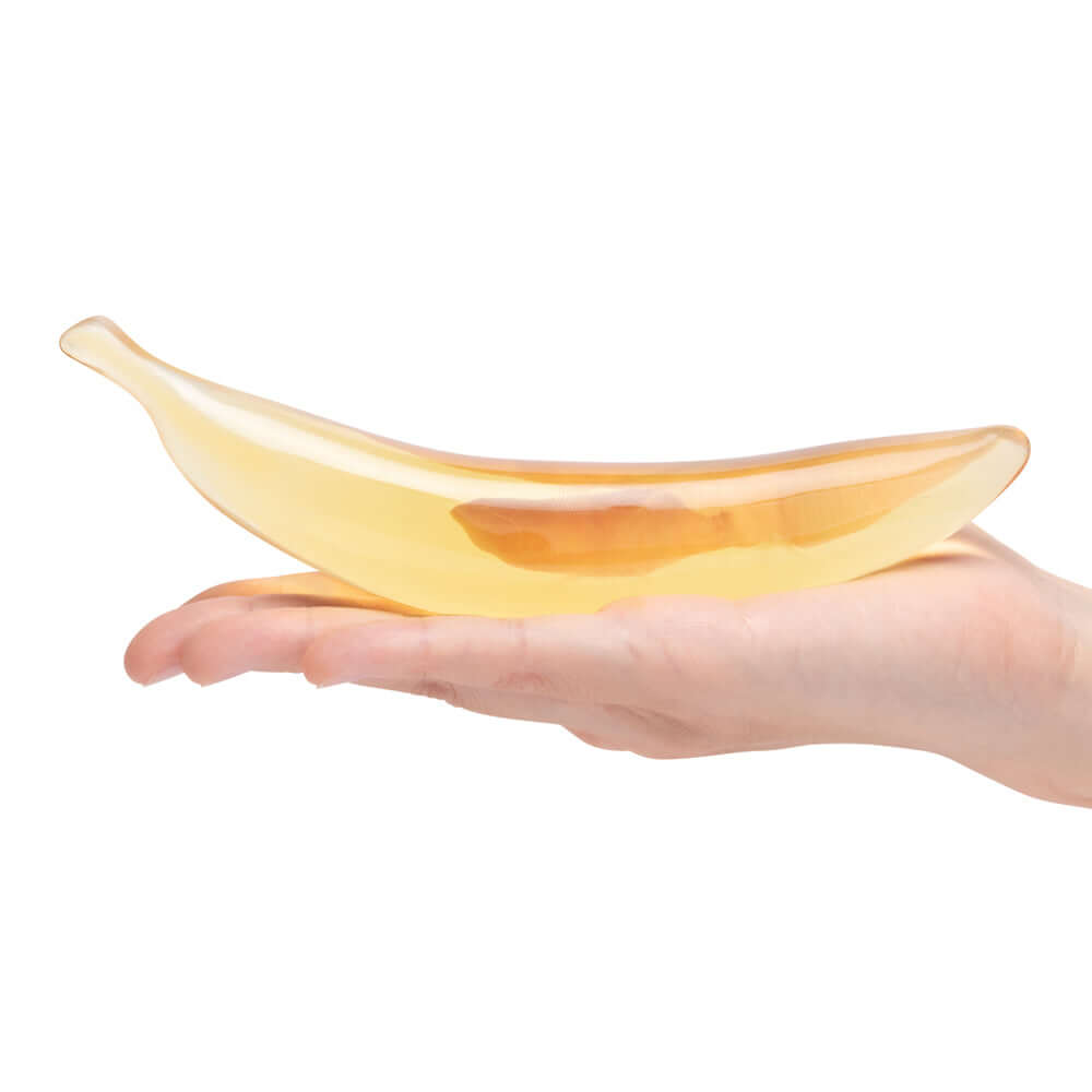 Glas Banana Joy 7 inches Glass Dildo held in hand, showcasing its whimsical design and vibrant color.