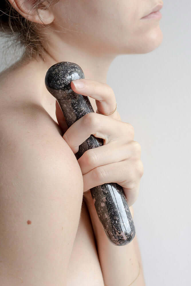 Chakrubs Anahata Curve Rhodonite Wand held close to the body, emphasizing its graceful curve and smooth texture.