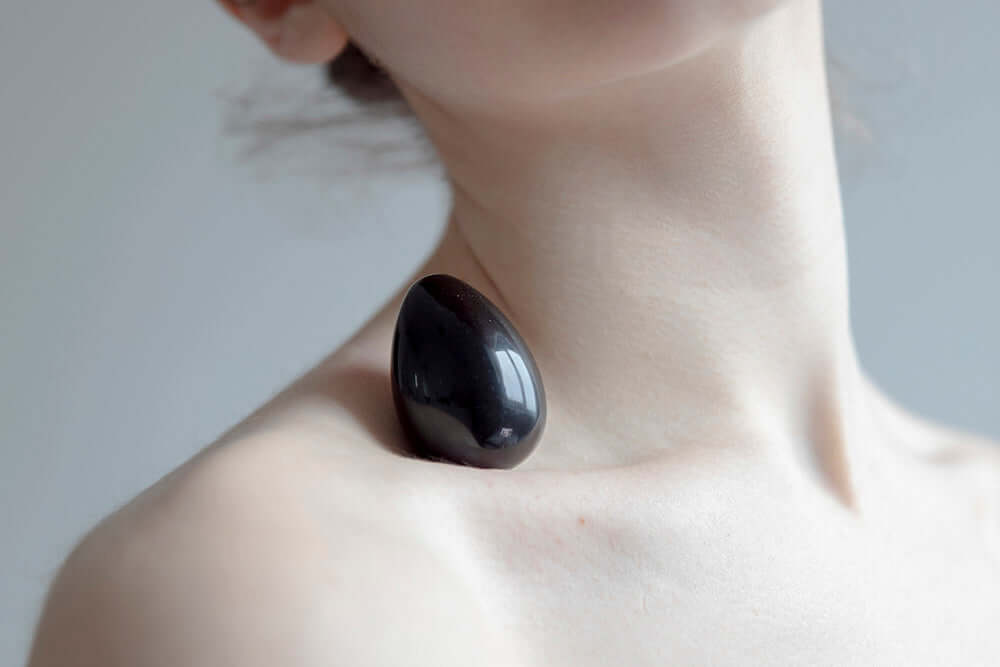 Chakrubs Xaga Yoni Egg Obsidian non-drilled resting on skin for body and spirit wellness.