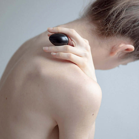Chakrubs Xaga Yoni Egg Obsidian non-drilled being held on a woman's shoulder for relaxation.