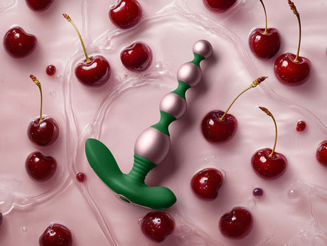 FemmeFunn Bougie Beads Rose Gold surrounded by cherries on a pink background.