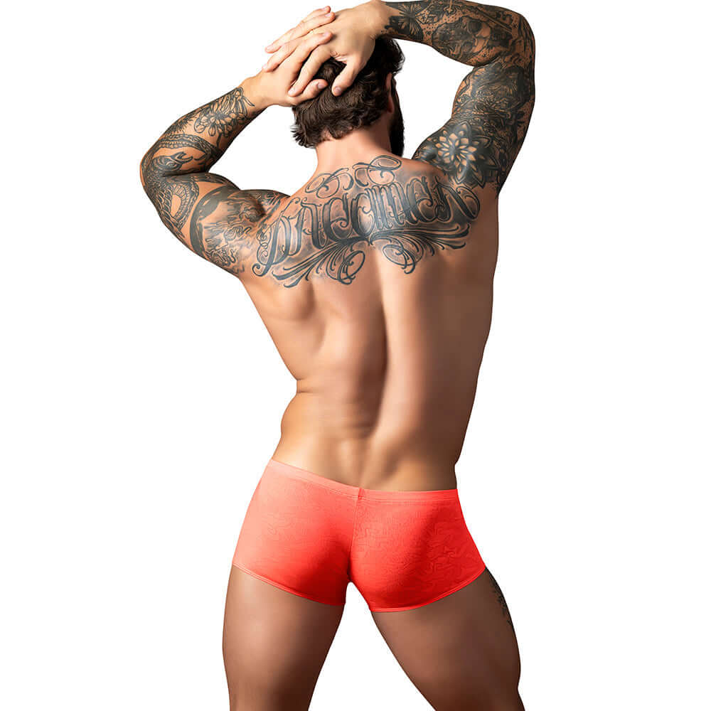 Male Power Kilauea Limited Edition Mini Short Coral L on a muscular man with tattoos, showcasing bold style and athletic fit.