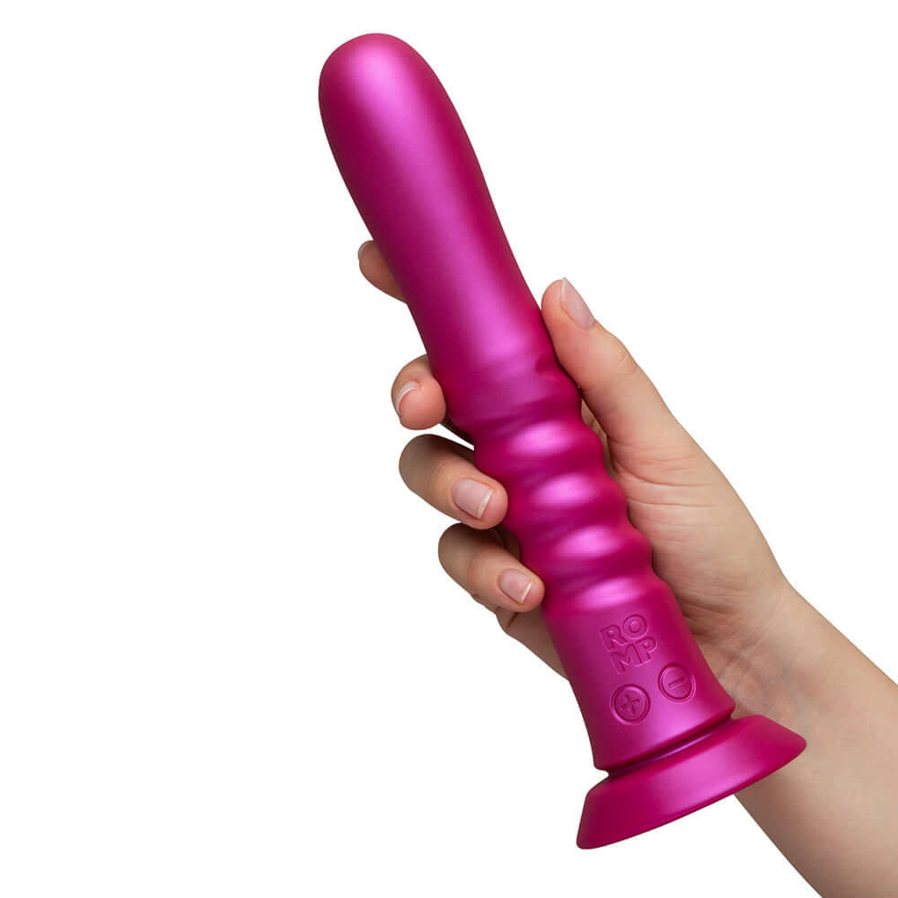 Romp Jiggle Thrusting Vibrator Pink held in hand showcasing its ergonomic design and suction cup base.