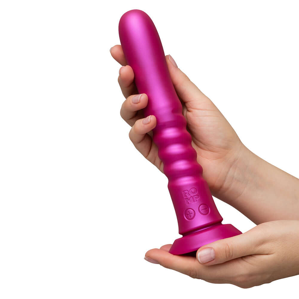 A person holding the Romp Jiggle Thrusting Vibrator Pink, showcasing its ergonomic design and powerful suction base.