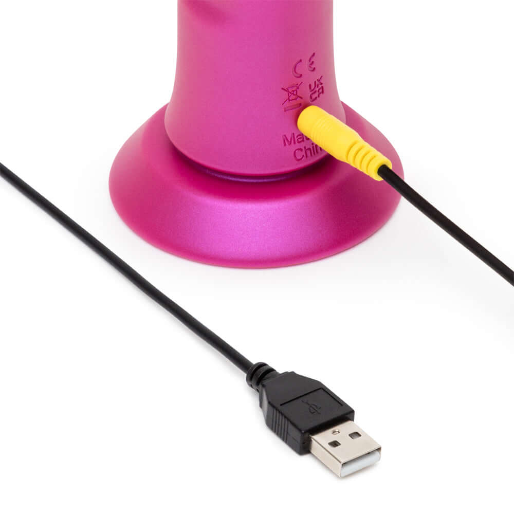Romp Jiggle Thrusting Vibrator Pink with USB charging cable connected to its suction cup base.