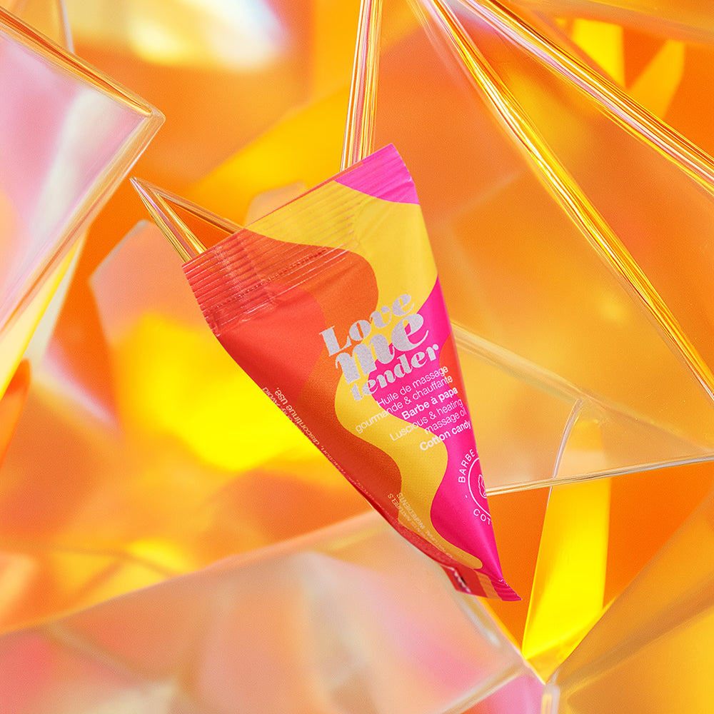 Love To Love Love Me Tender Heating Massage Oil Cotton Candy in colorful packaging on a vibrant background.