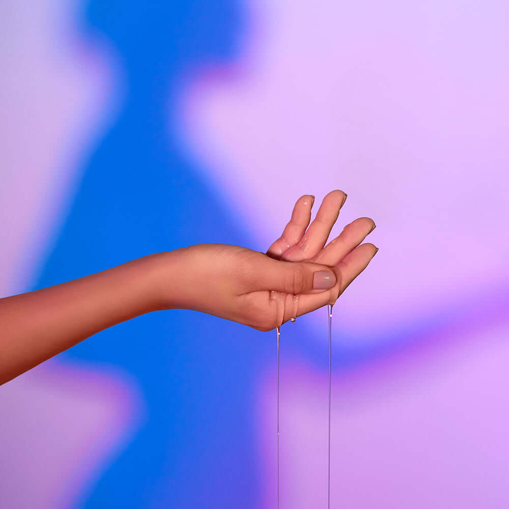 Love To Love Love Me Tender Heating Massage Oil Vanilla drizzling from a hand, highlighting its warm, sensual texture.