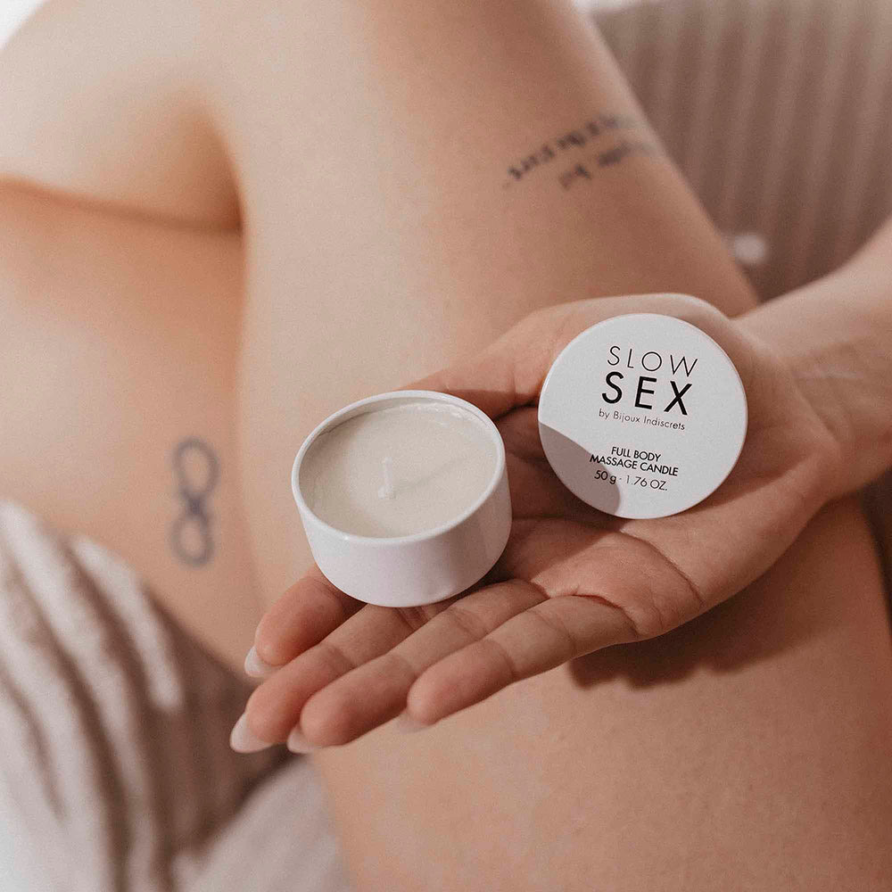 Bijoux Indiscrets Slow Sex Massage Candle in a hand, showcasing a sensual massage experience.