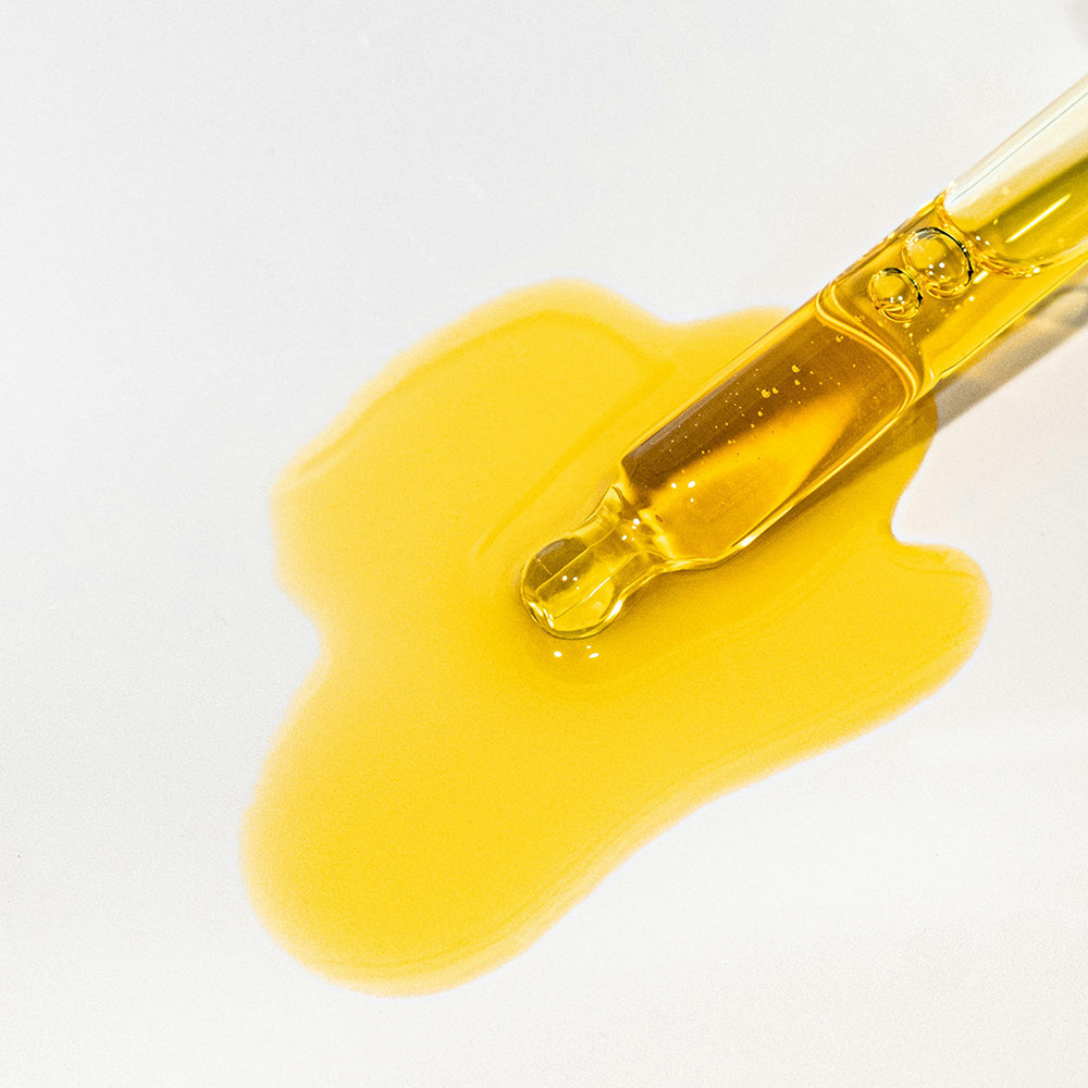 Slow Sex Anal Soothing Oil Before And After Care dropper with golden oil on a white surface.