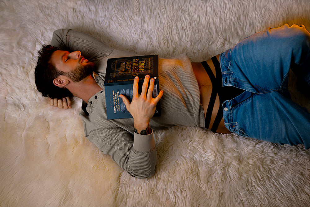 Male Power Eco Cozy Cutout Thong Green L/XL worn by a man lounging with a book on a cozy fur blanket.