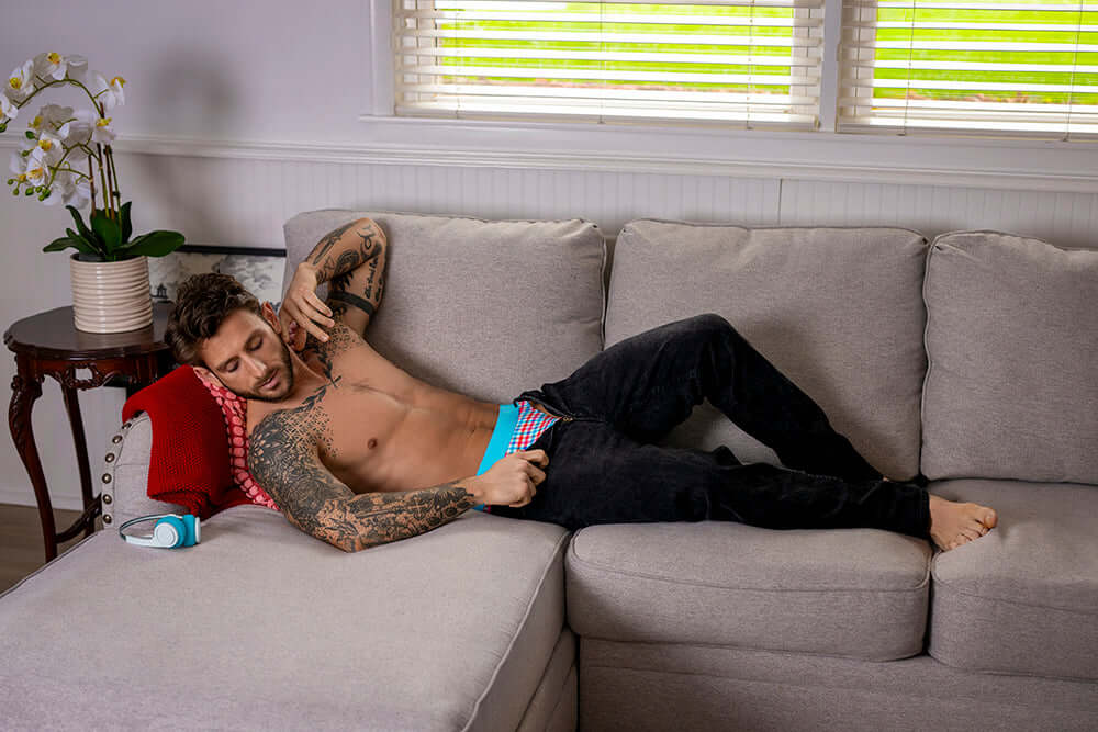 Male Power So Cumfy Gingham Thong Turquoise S M model lounging on a couch, showcasing the vibrant design and comfort.