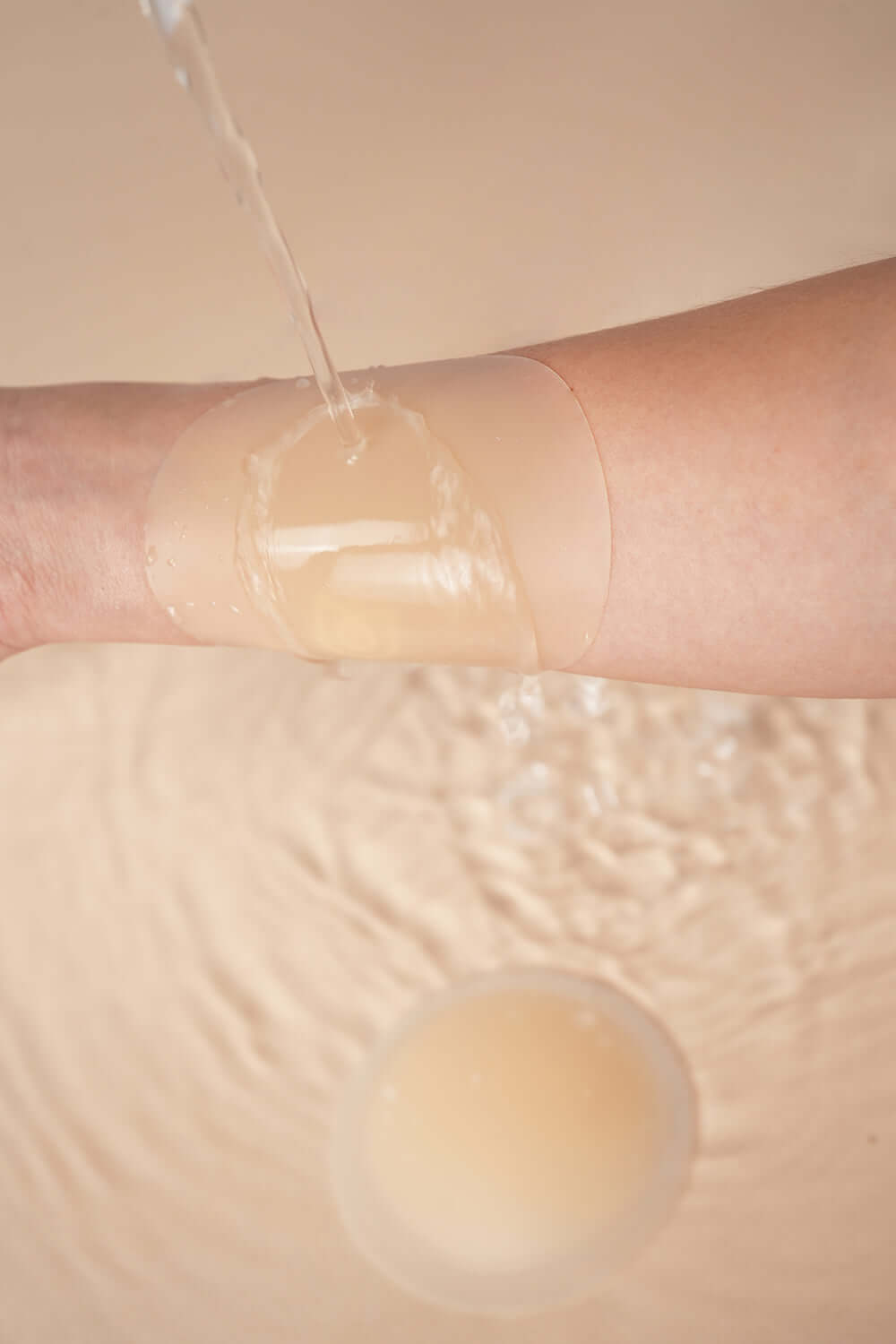 Uva Circular Nipple Covers Nude demonstrating waterproof coverage on skin with water splashing.