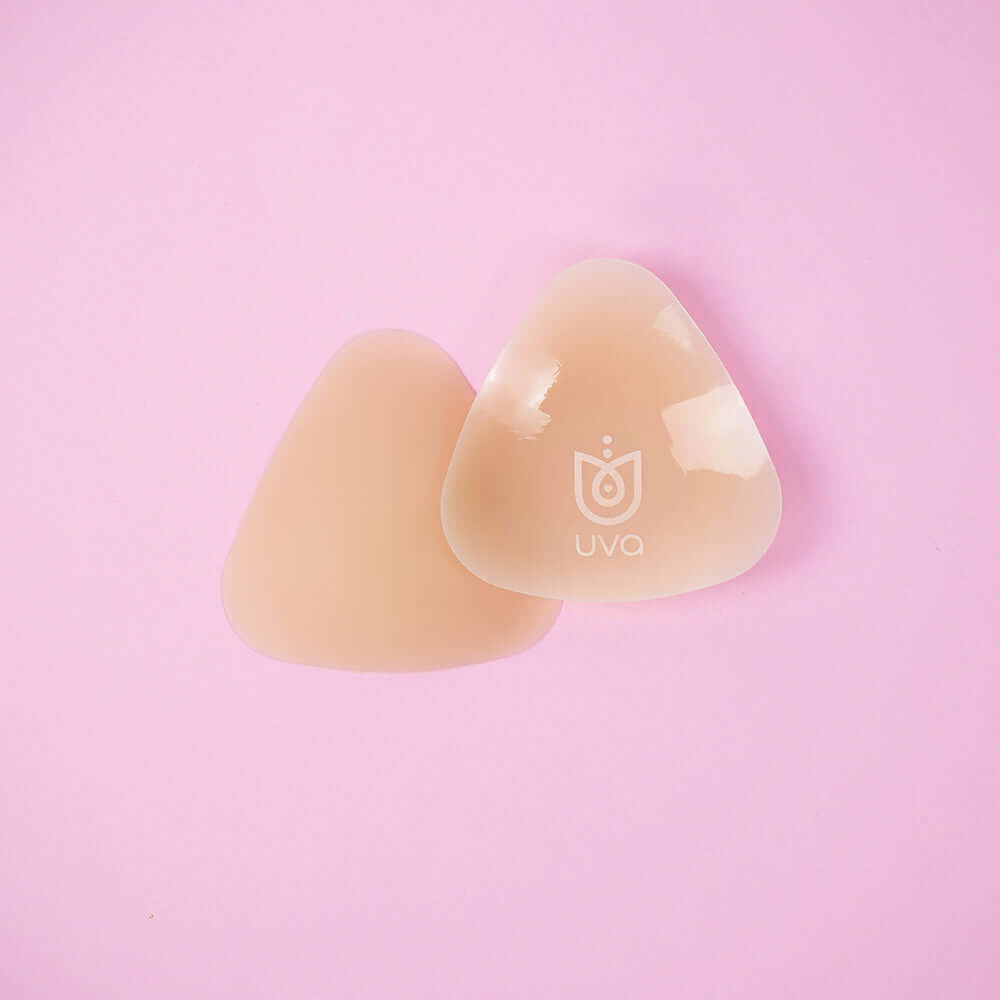 Uva Triangular Nipple Covers Caramel on a pink background for discreet coverage under clothing.