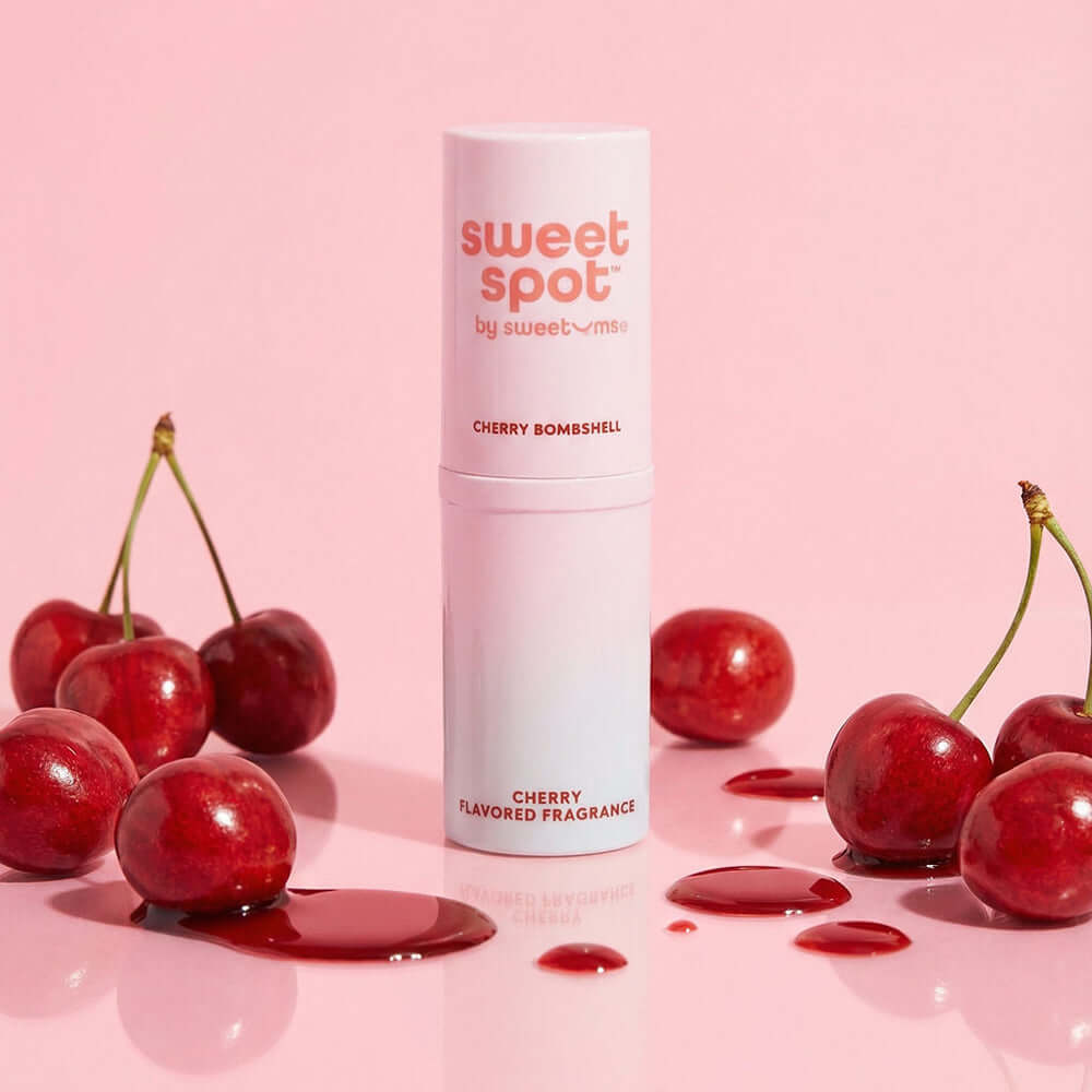 Sweetums Sweet Spot Flavored Fragrance Cherry Bombshell with cherries on a pink background, showcasing the playful scent.