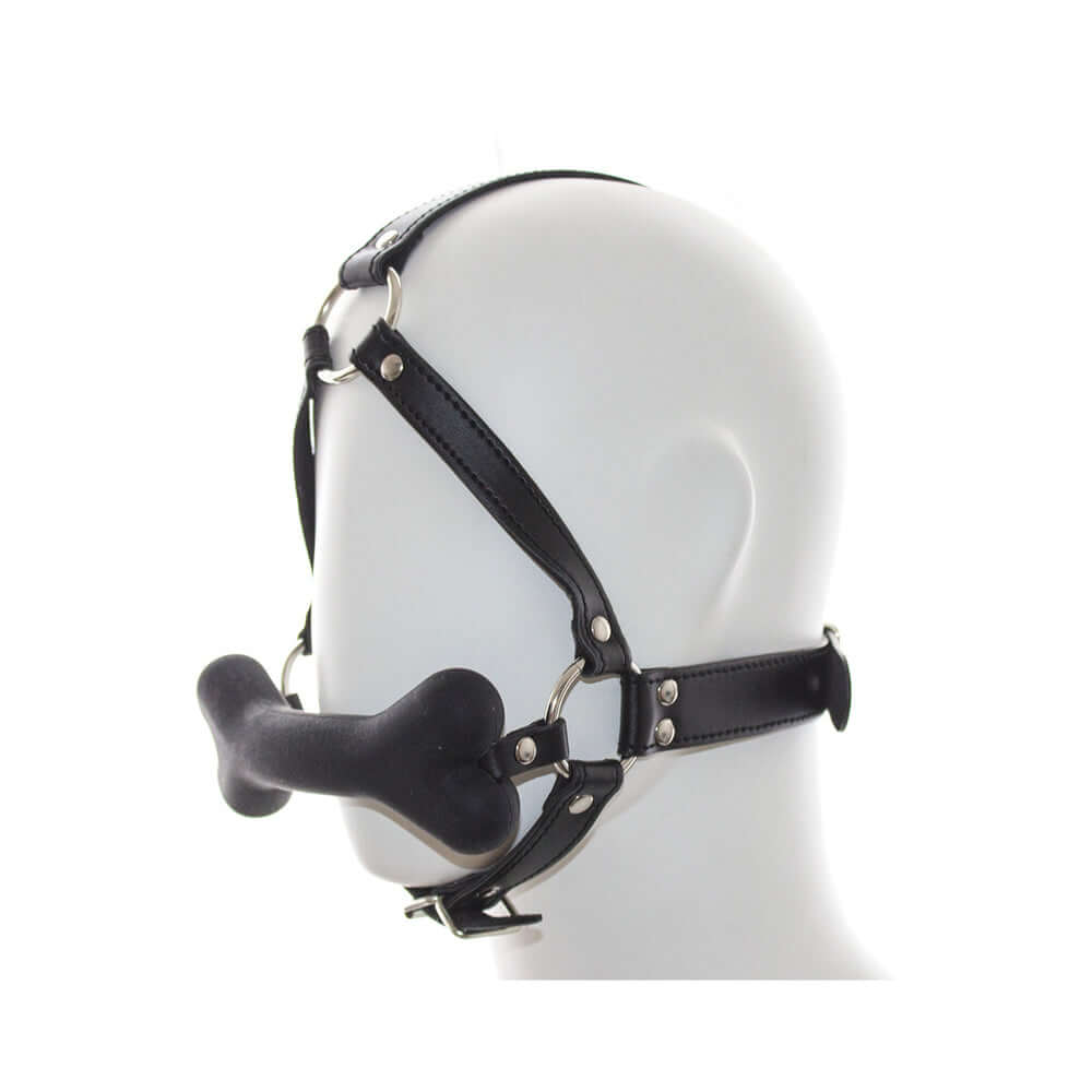 Ple'sur Face Harness Dog Bone Gag shown on a mannequin head, featuring a black harness and playful bone gag.