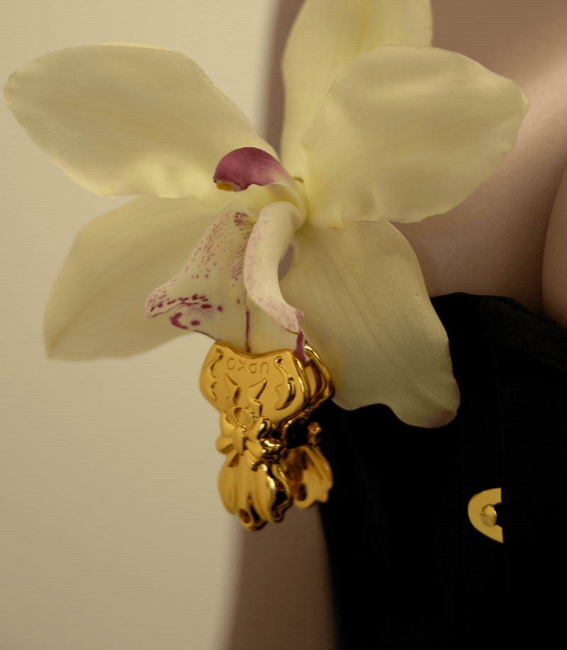Elegant bowknot binder clip style nipple clamps adorned with a yellow orchid, showcasing unique design and intricate details.