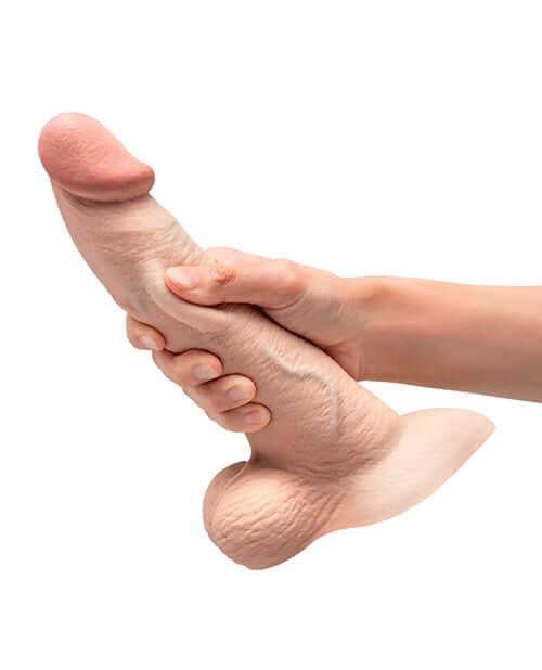 Hand holding the b-Vibe Slipskin 9 inches Curvy Dildo Cream showcasing its realistic shape and texture.