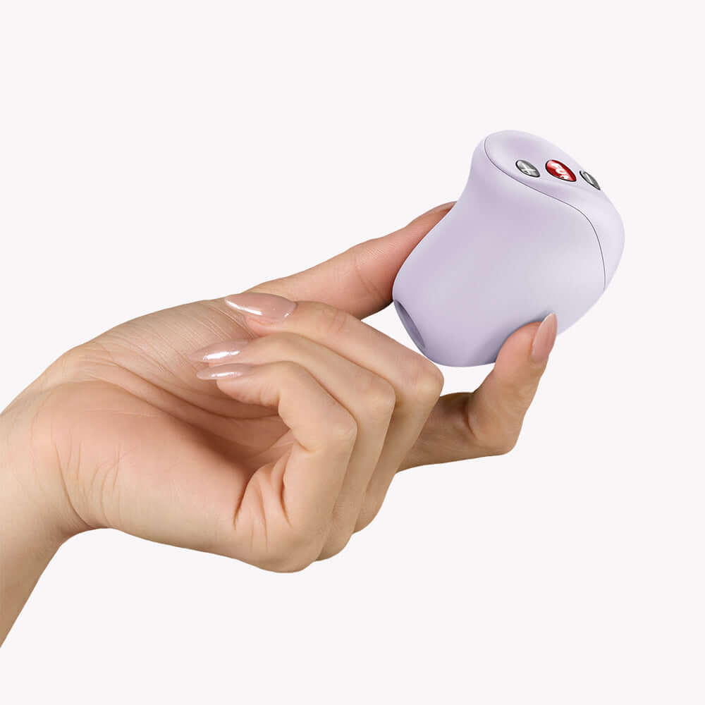 Person holding Fun Factory Mea Air Pulse Clitoral Vibrator Purple in hand with control buttons visible.