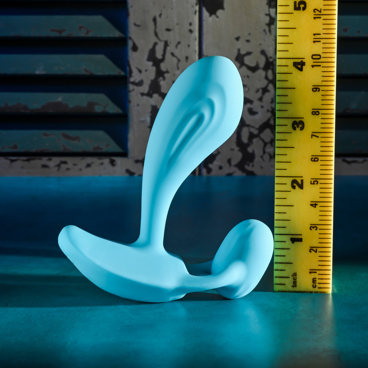 Gender X Wear Me Out Wearable Dual Vibrator Blue displayed next to a measuring ruler for size reference.