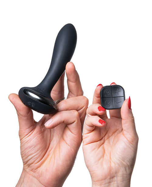Hot Octopuss PleX with Flex Butt Plug Black held in hands with remote control for customizable vibrations.