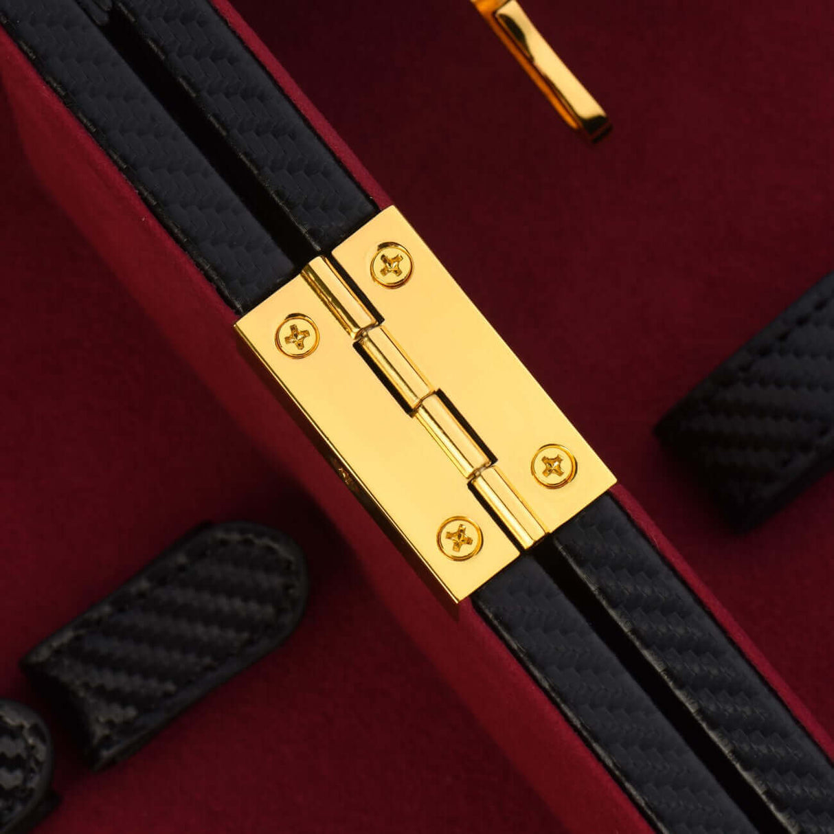 Close-up of the luxurious gold hinge on the UPKO luxury bondage trunk with red velvet lining.