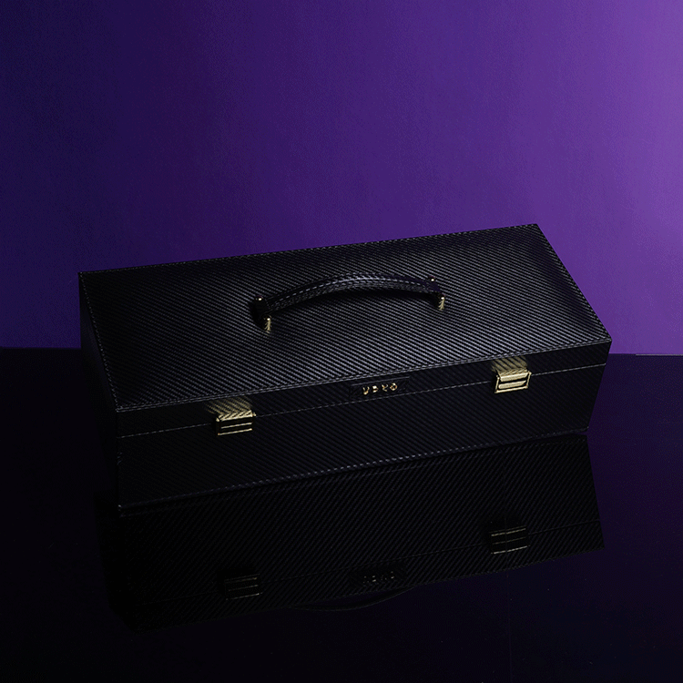 Luxury black leather bondage tools case from UPKO on a reflective surface with a purple background.
