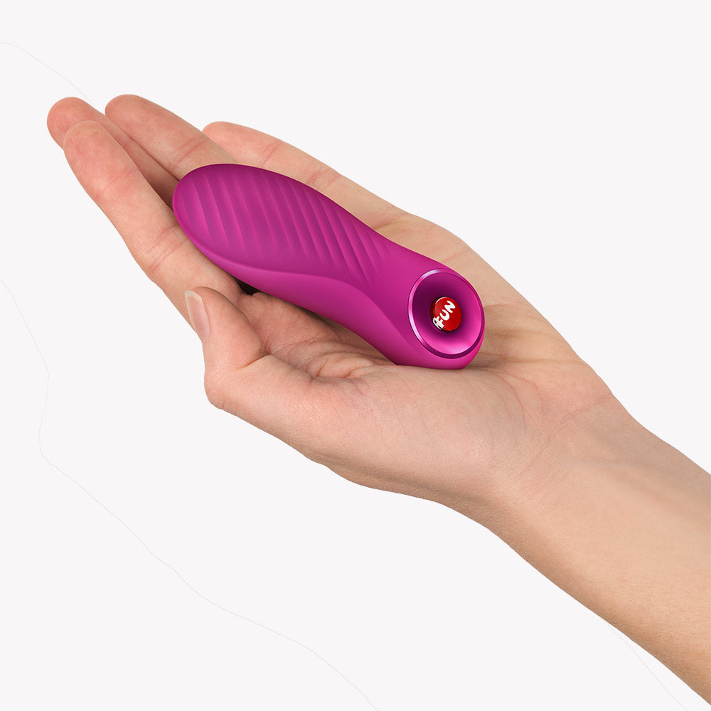 Fun Factory Bijou Bullet Vibrator Magenta held in a hand, showcasing its compact design and textured surface.