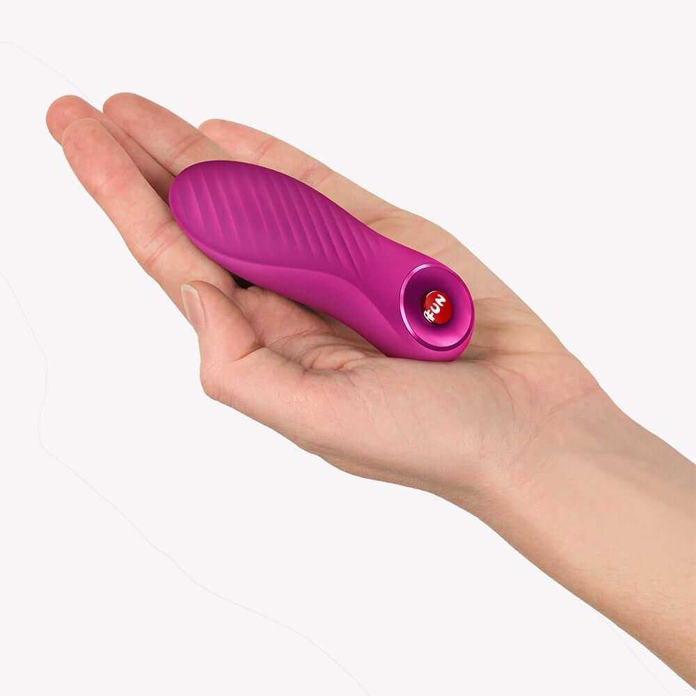 Fun Factory Bijou Bullet Vibrator Magenta held in a hand, showcasing its compact design and textured surface.