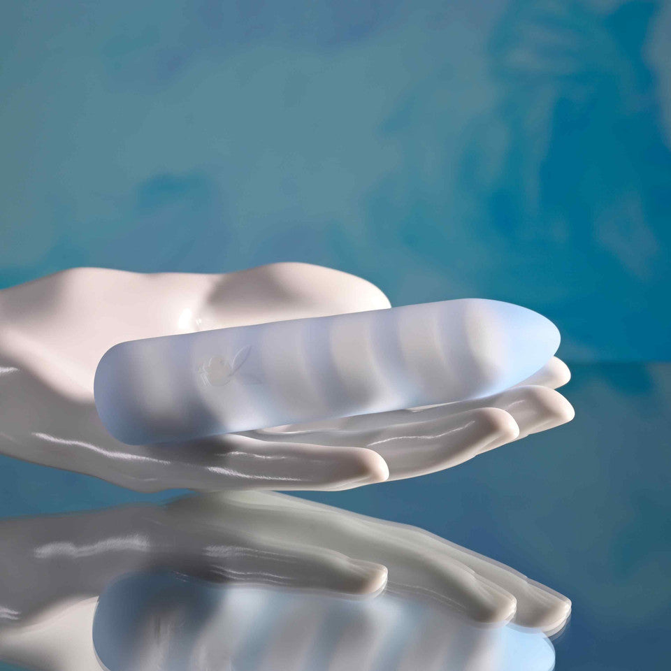 Playboy Unicorn Vibes Silicone Vibrating Bullet Blue resting in a hand against a soft blue background.