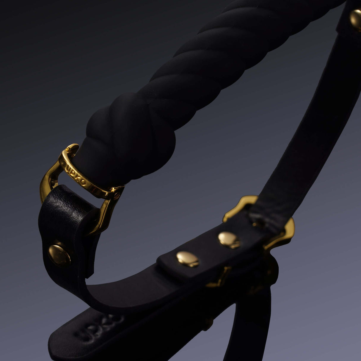 Black UPKO knot-shaped mouth gag with gold hardware, featuring premium silicone and Italian leather for luxury and secure fit.