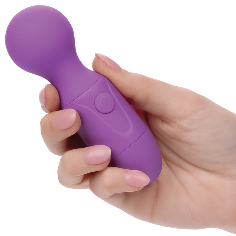 A hand holding the First Time Rechargeable Silicone Massager Purple, showcasing its compact size and design.