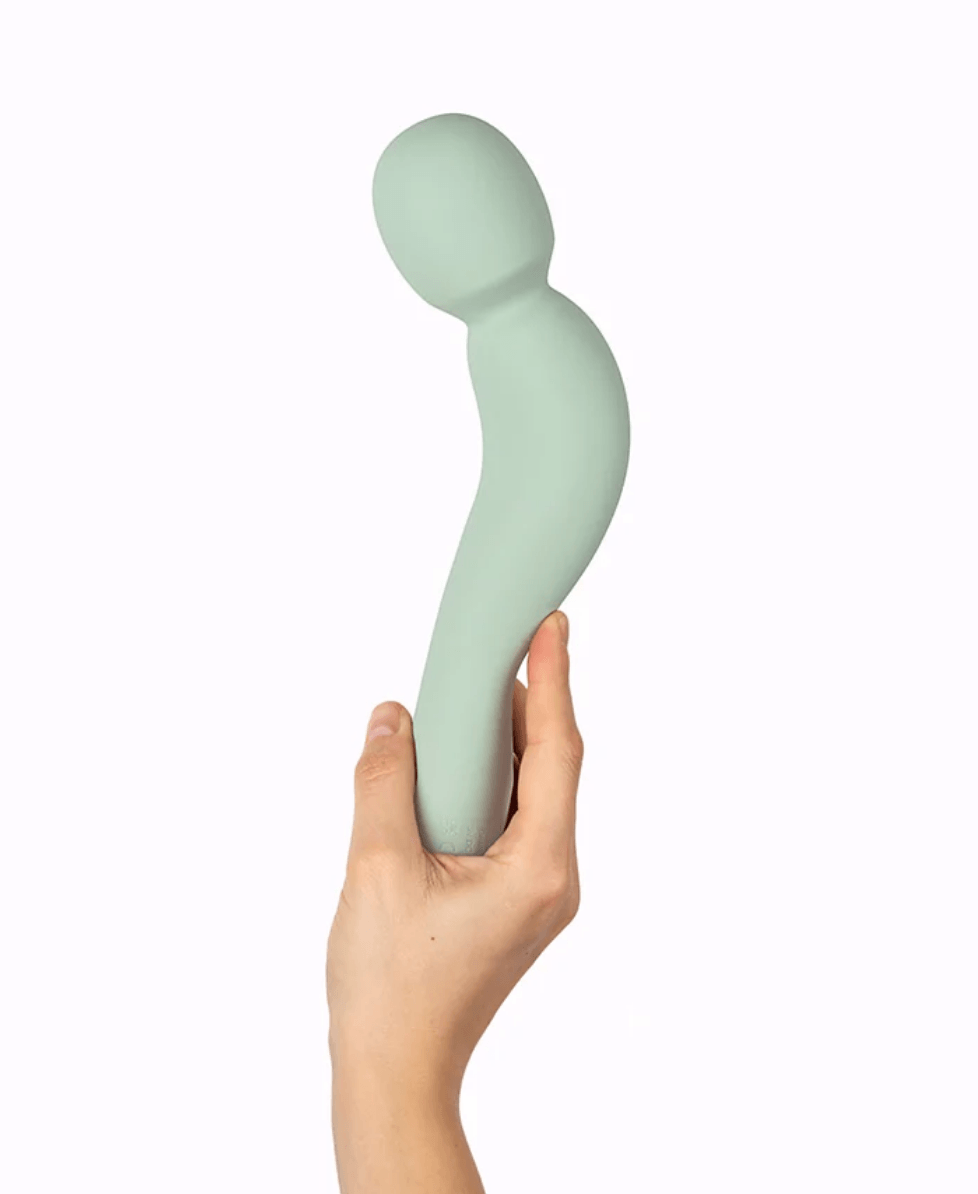 Dame Com Wand Vibrator Sage held in hand, showcasing its ergonomic design and soothing sage color.