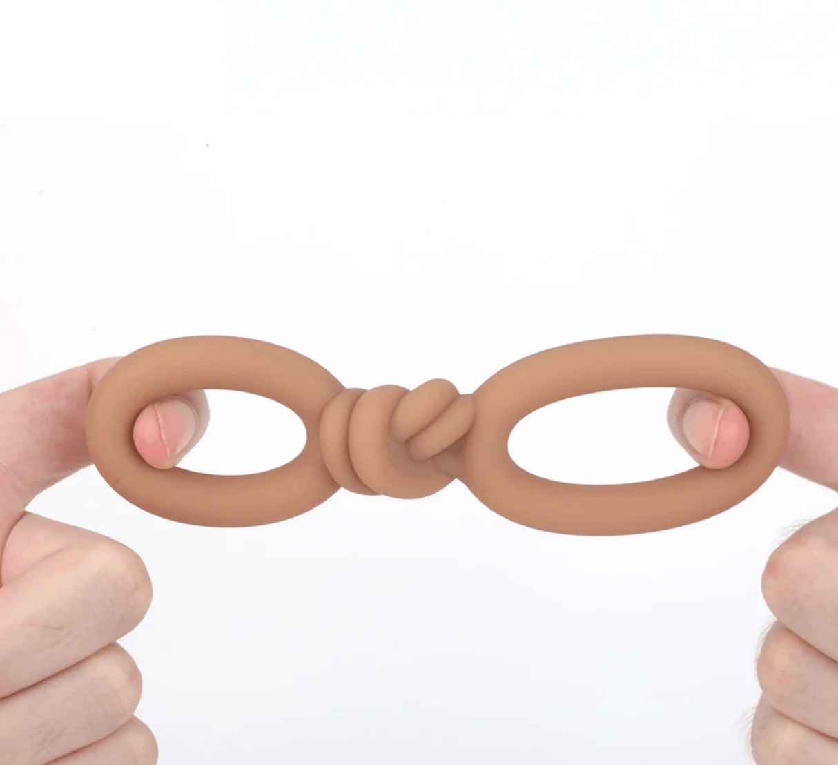 Maia Cooper Liquid Silicone Dual Super Stretch C-Ring Caramel held between two fingers, showcasing its flexible design.