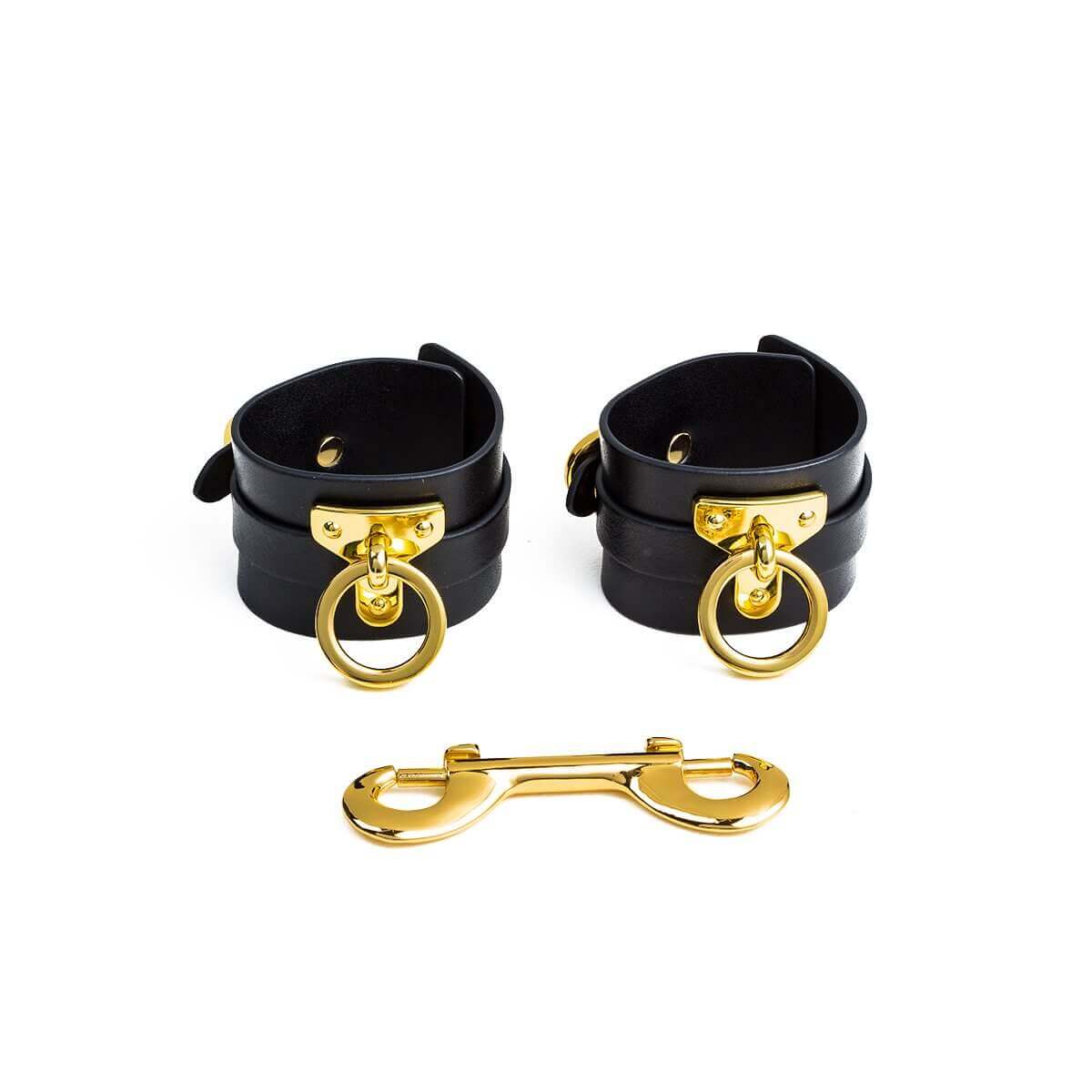 Luxury black leather wrist cuffs with golden hardware for bondage play, ideal for BDSM enthusiasts.