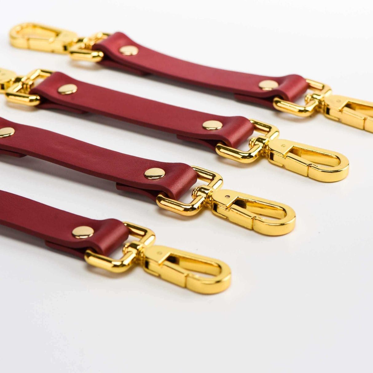 Red Italian leather bondage straps with golden clips, part of the UPKO luxury BDSM tools set.
