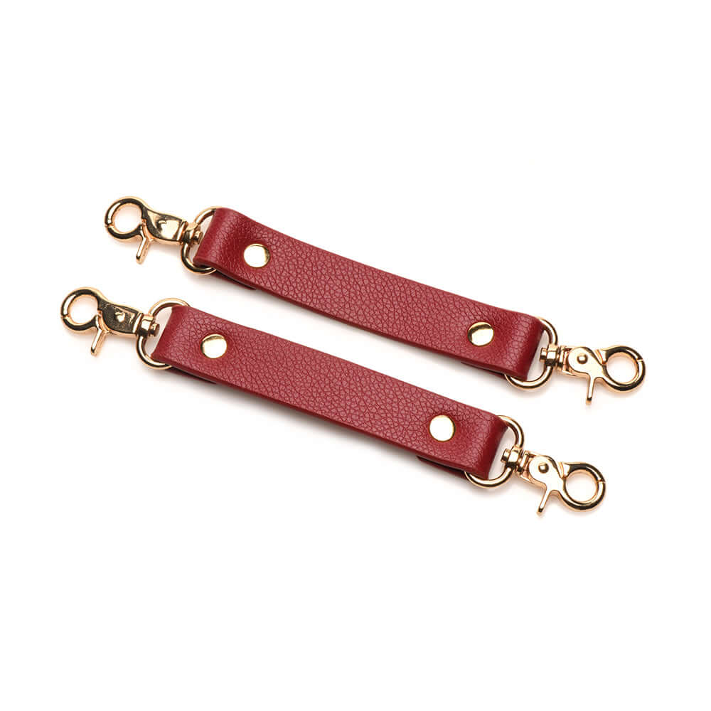 Red vegan leather cuff connectors with gold hardware for bondage or restraint play.