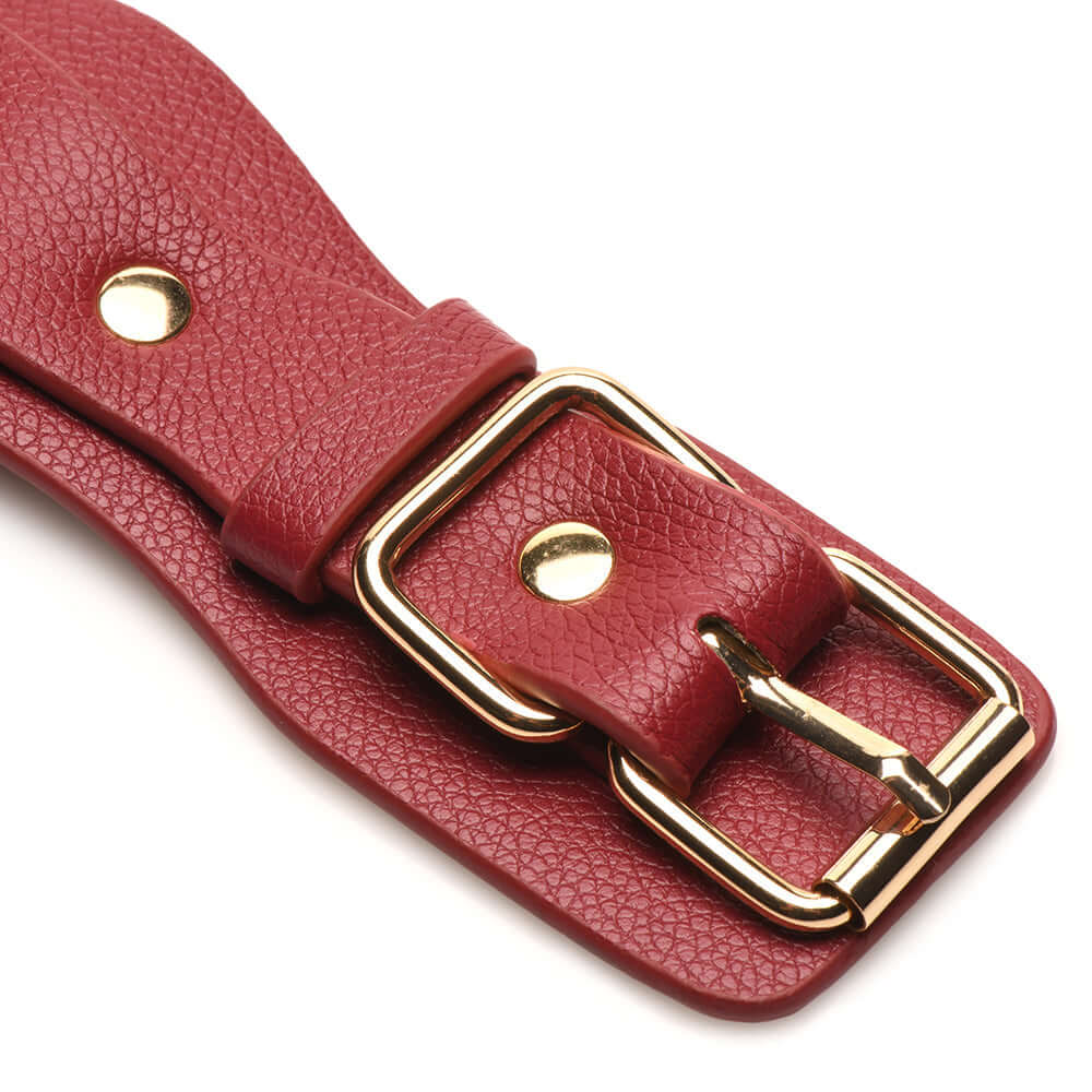 Close-up of adjustable red vegan leather strap with gold buckle for restraints set